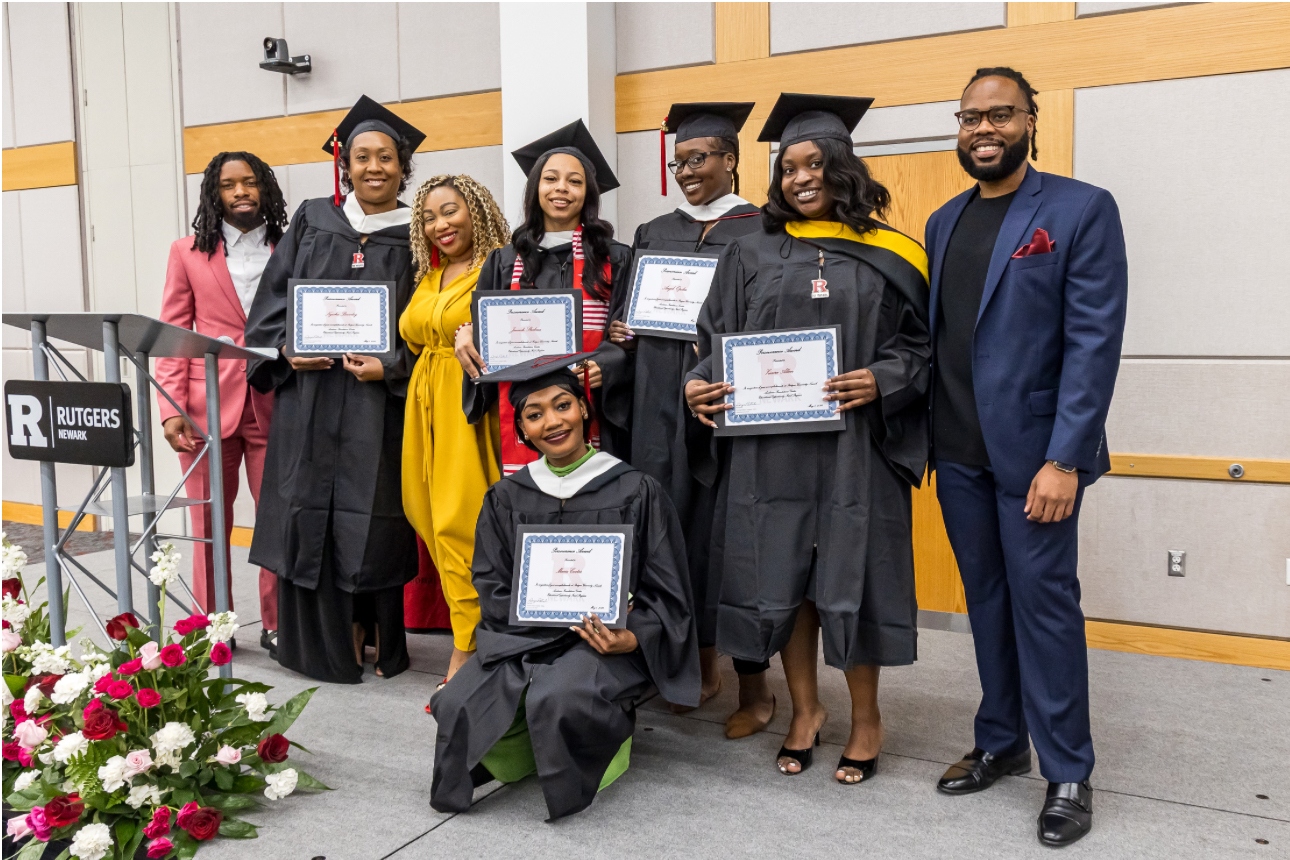 Group graduation photo at Rutgers University with Maria kneeling in the front row